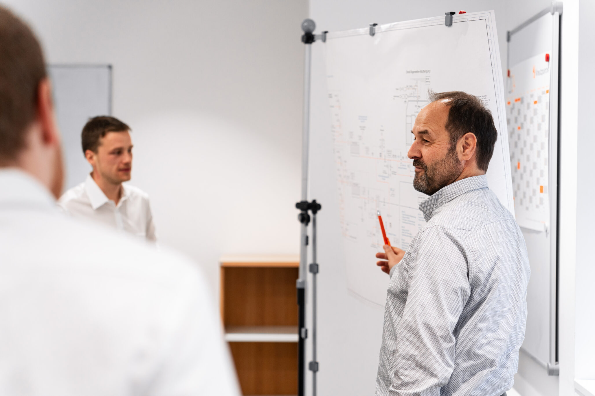 Ingenieur erläutert elektrotechnische Pläne an einem Whiteboard – Kreutzpointner.