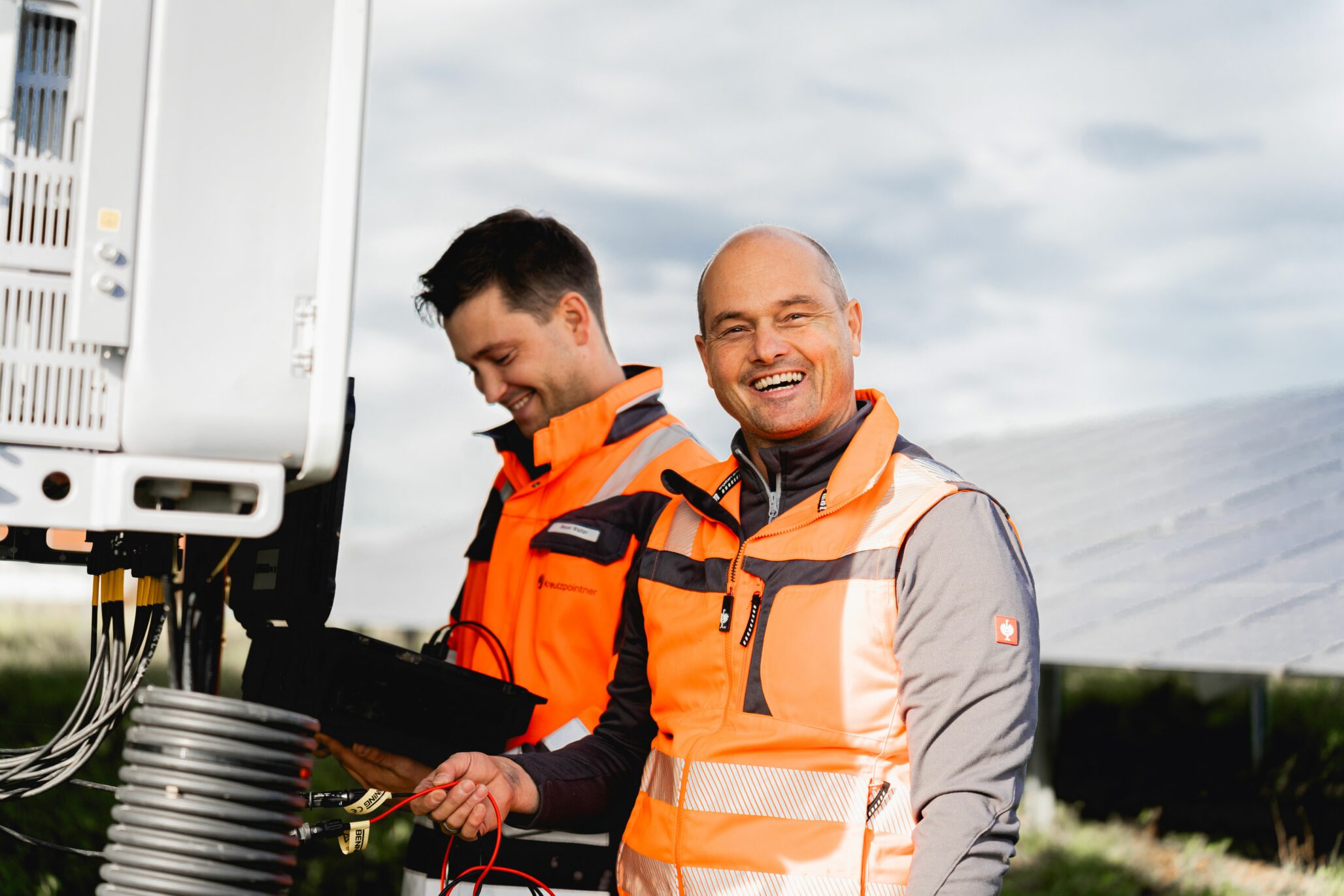 Zwei Mitarbeiter in Arbeitskleidung bei der Umsetzung eines erneuerbaren Energieprojekts.