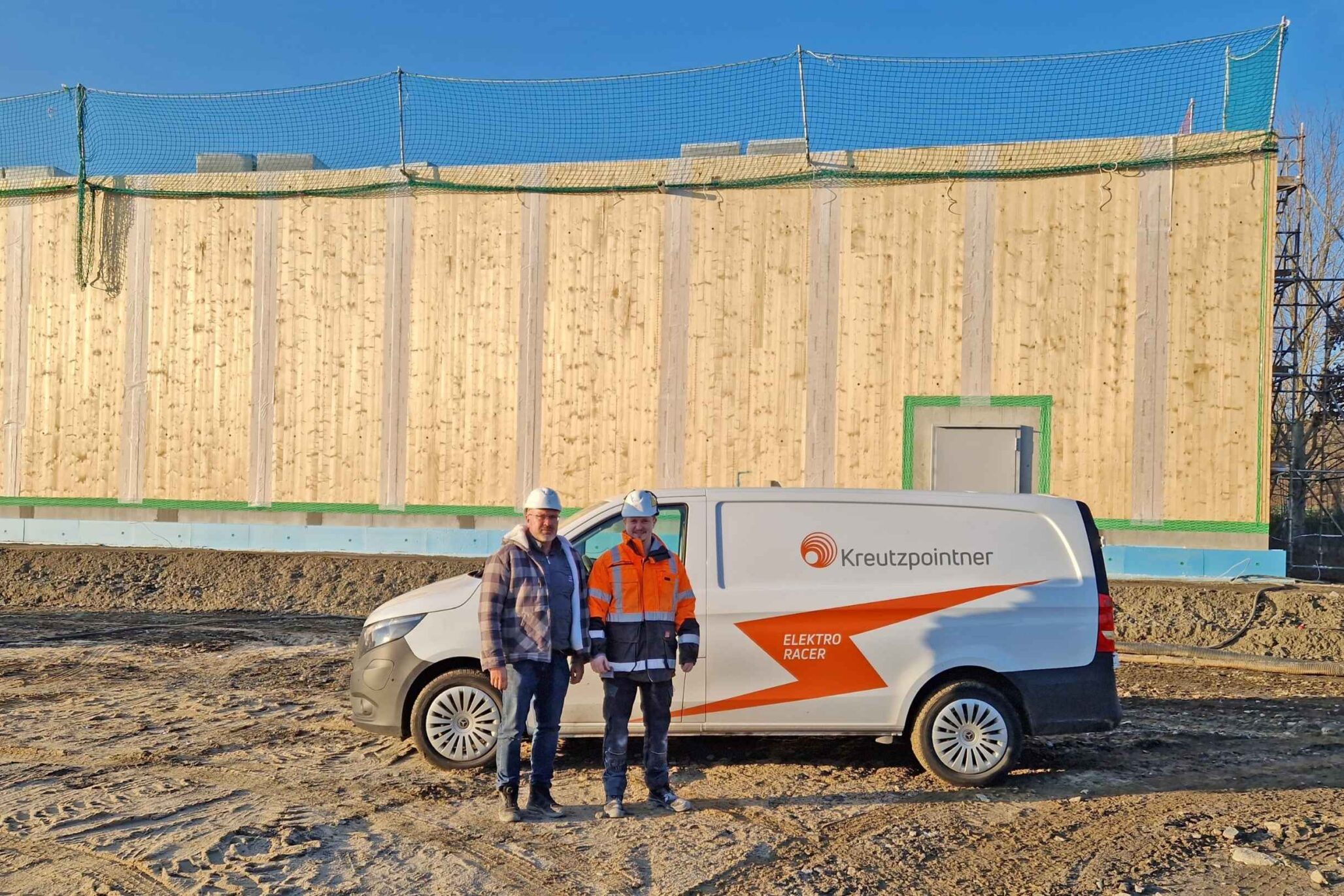 Zwei Bauleiter vor einer Holzrahmenkonstruktion des neuen Jägermeister-Lagers, das in zertifiziert-nachhaltiger Bauweise errichtet wird.