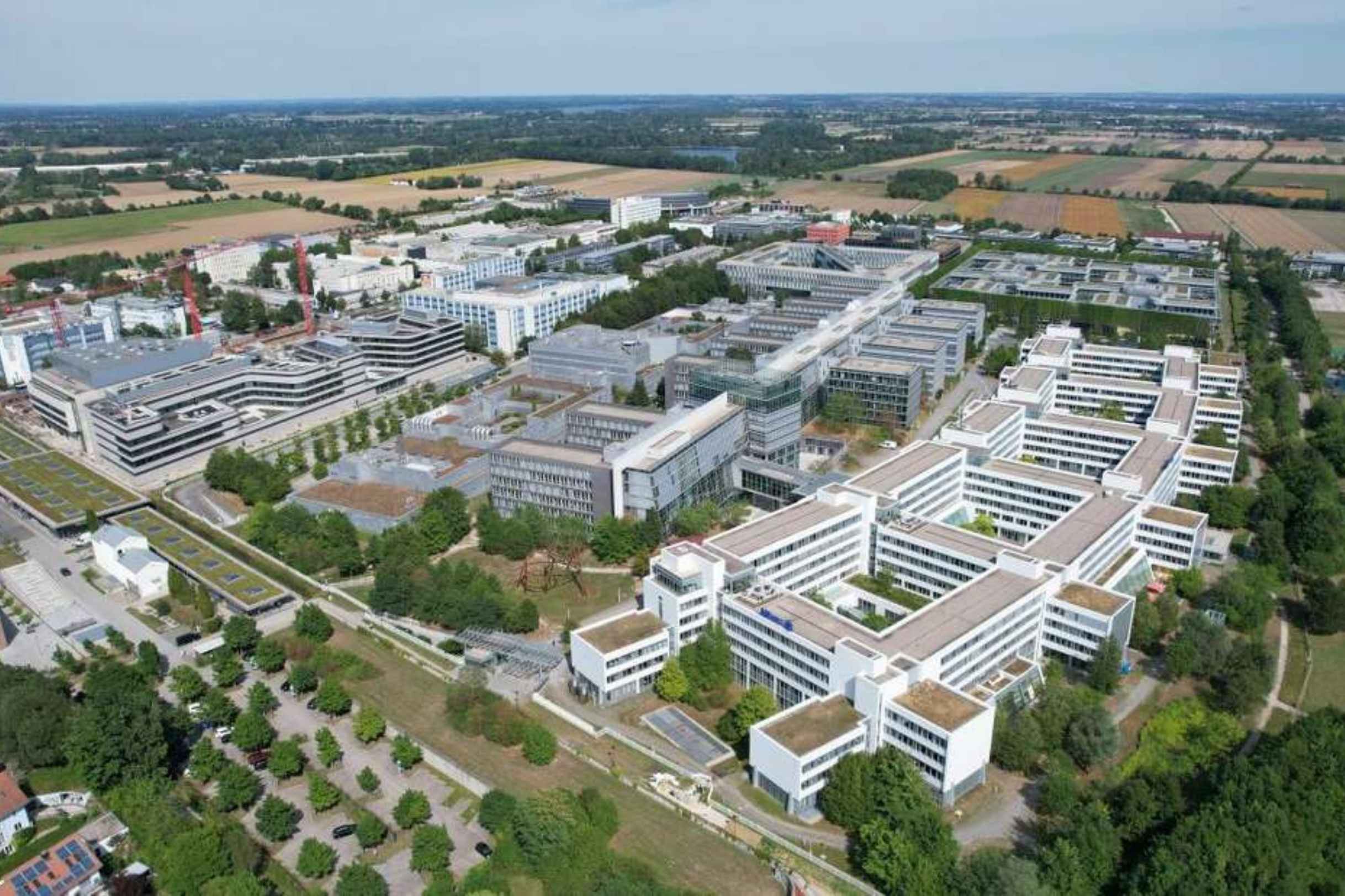 Luftaufnahme des Allianz-Campus in München-Unterföhring mit modernen Bürogebäuden, begrünten Dächern und weitläufiger Umgebung.