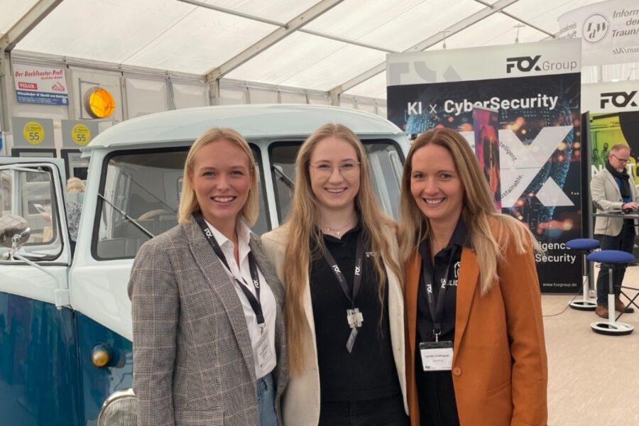 Drei Frauen auf einer Messe stehen vor einem alten VW Bus.