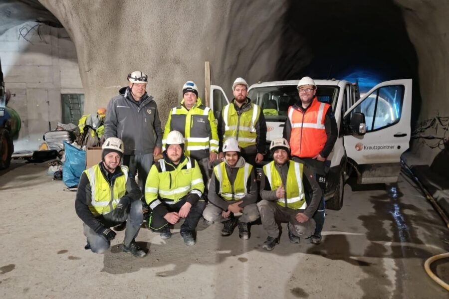 Ein Montageteam in Arbeitskleidung sitzt vor einem Fahrzeug in einer Gewölbe, wie in einer Höhle.