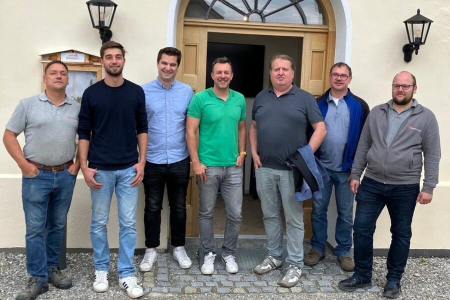Gruppenbild einer Männergruppe vor einem Gebäude mit offener Tür.