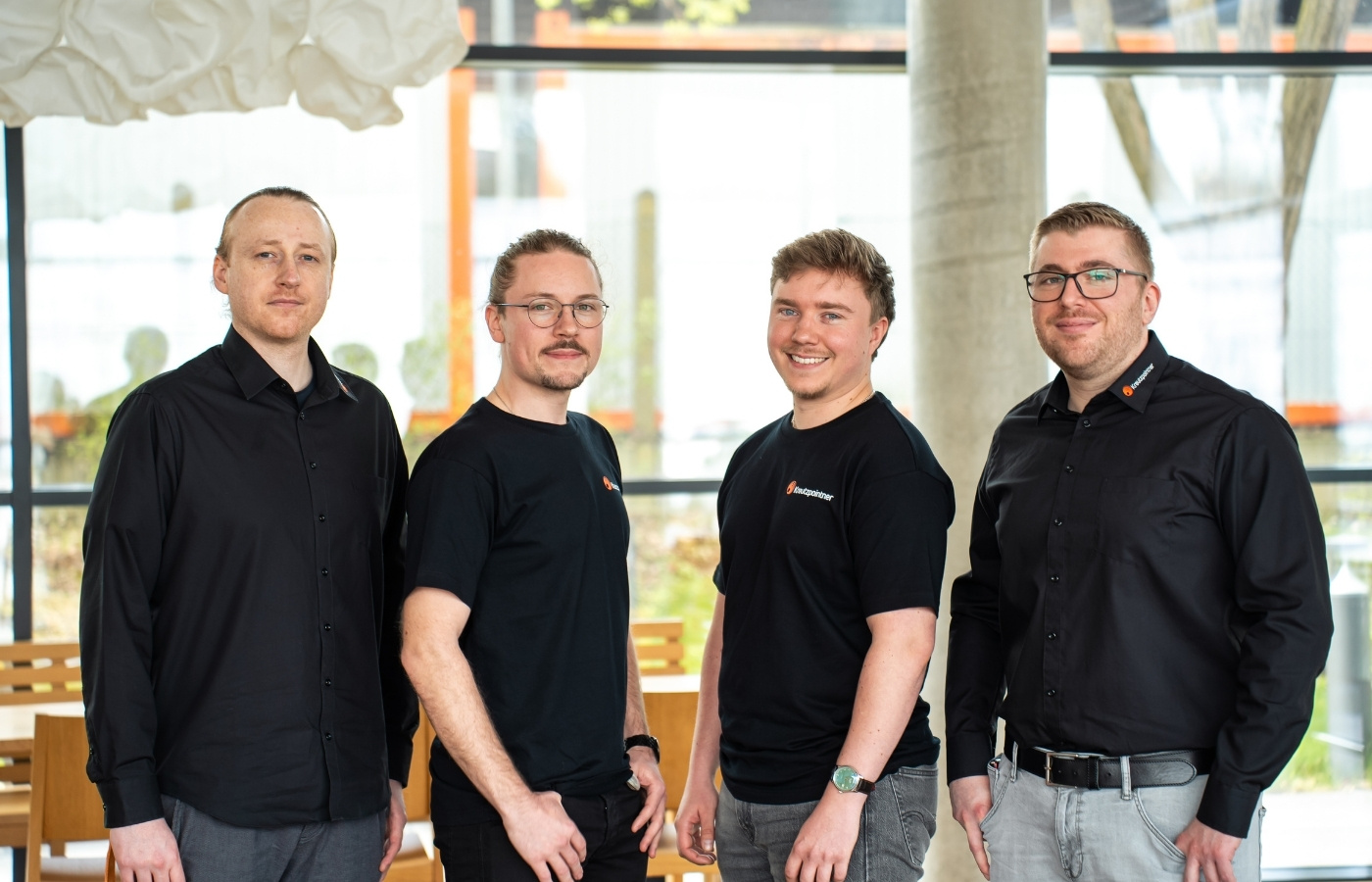 Gruppenbild von 4 Herren, dunkel gekleidet und lachen in die Kamera.