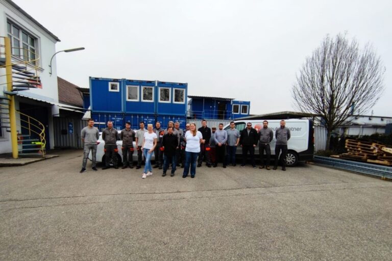 Ein Gruppenfoto mit blauen Containern im Hintergrund.