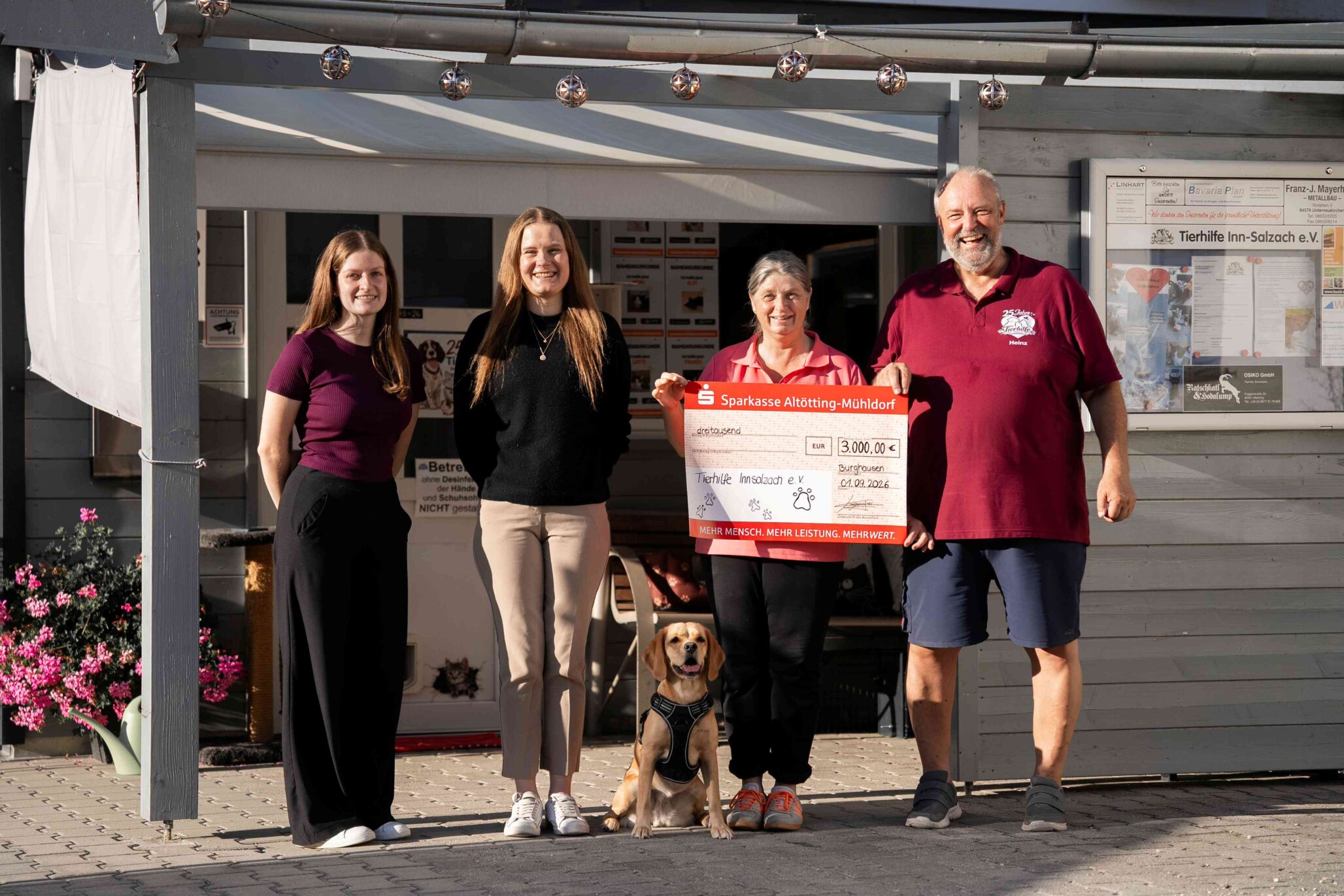 Gruppenfoto mit 4 Personen und einem Hund der zwischen den Beinen sitzt.
