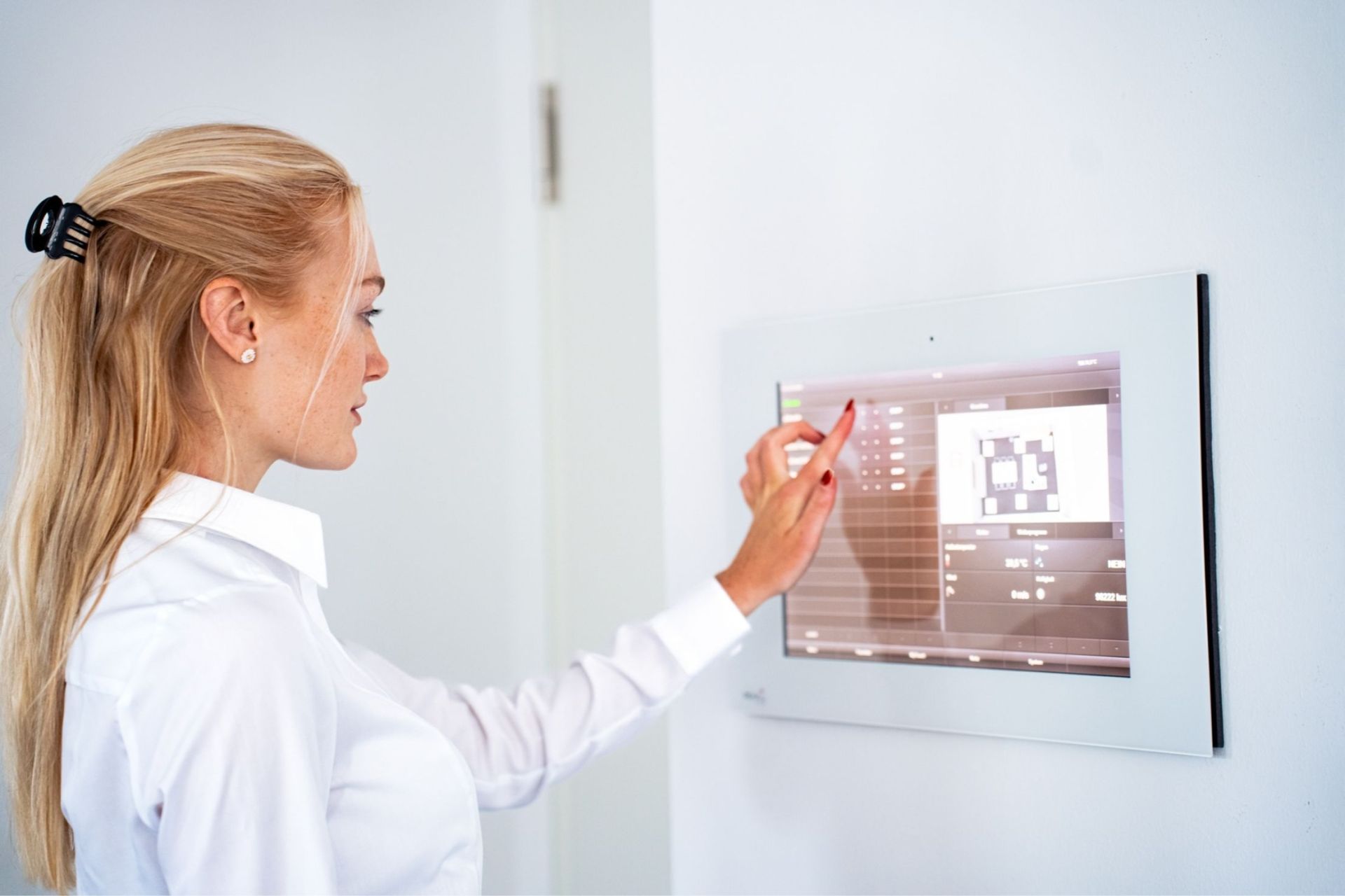 Frau bedient ein modernes Touchpanel für Gebäudeautomation – Kommunikations- und Medientechnik von Kreutzpointner.